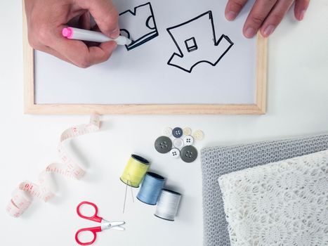 Sewing accessories, fabric and white board with sketches on a white background with space for your idea text.