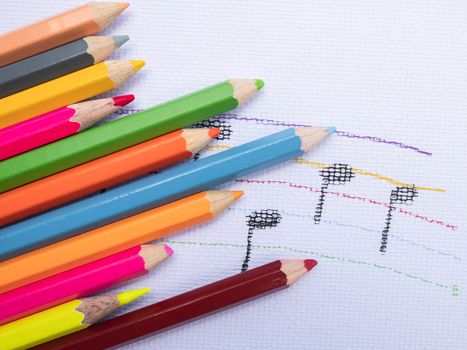 Color pencils place on white paper background with Music note drawing. Education concept.