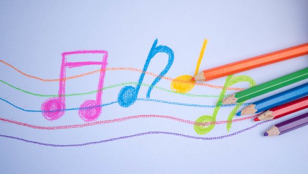 Color pencils place on white paper background with Music note drawing. Education concept.