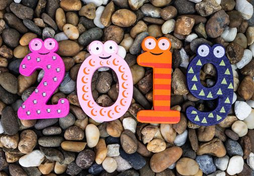 Pebbles pattern or small stones background in garden with colorful Arabic wooden numbers; 2019. Concept of new year and textured.