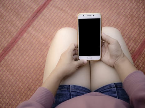 Woman hand holding smartphone over wooden table background with space for your text.