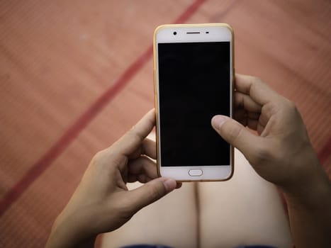 Close up of hand holding smartphone over wooden table background with space for your text.