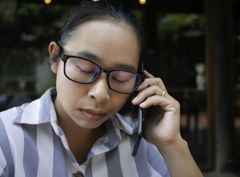 Stressed Asian young woman talking on the phone at coffee cafe.
