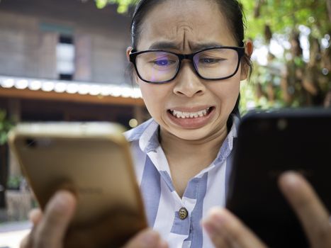 Business Asian young woman holding 2 smartphone do busy with work, Unhappy and worry face.