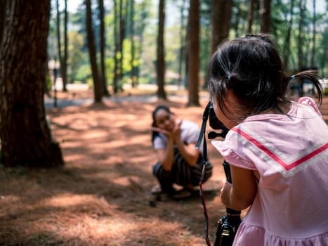 Asian little child use camera is taking photo for her mother at pine forest in Chiang Mai, Thailand. Relaxation travel concept.