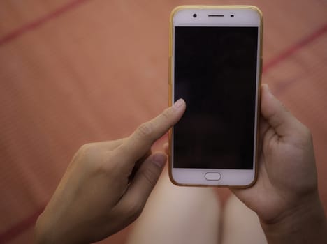 Close up of hand holding smartphone over wooden table background with space for your text.