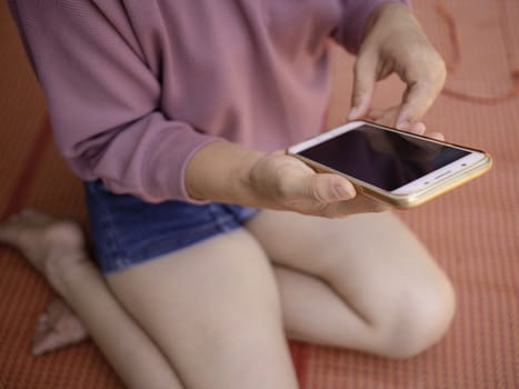 Woman hand holding smartphone over wooden table background with space for your text.