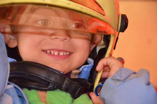 Little boy acting like a fireman. Boy putting fire helmet on head. Dreaming of future profession. Fire safety, life protection lessons. Close-up.