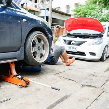 Bangkok, Thailand - August 30, 2015 : Unidentified serviceman checking suspension in a car at garage