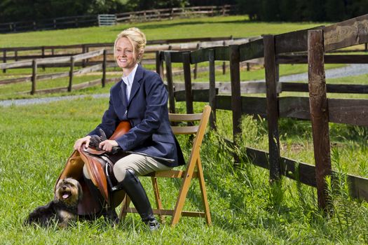 A blonde equestrian model poses outdoors before a horse show