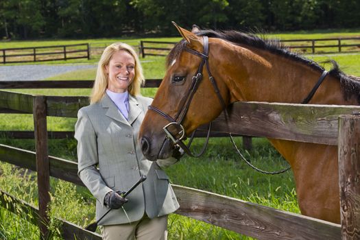 A blonde equestrian model poses outdoors before a horse show
