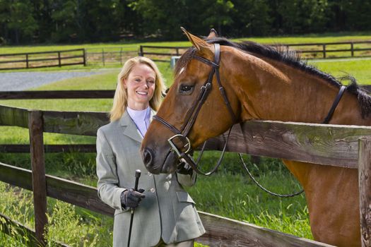 A blonde equestrian model poses outdoors before a horse show