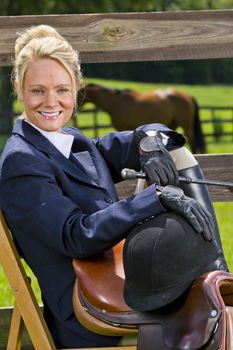 A blonde equestrian model poses outdoors before a horse show