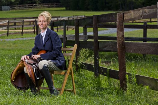 A blonde equestrian model poses outdoors before a horse show