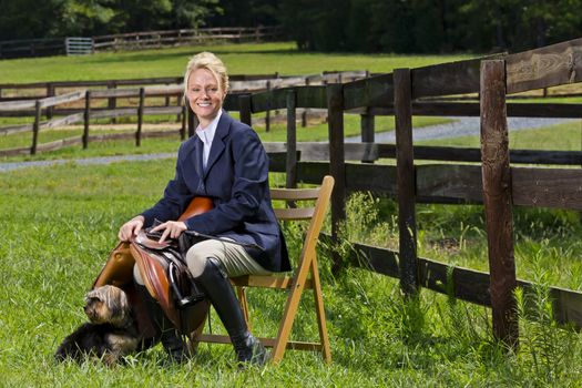 A blonde equestrian model poses outdoors before a horse show