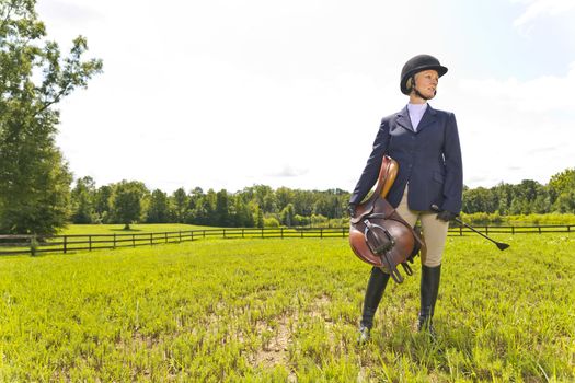 A blonde equestrian model poses outdoors before a horse show