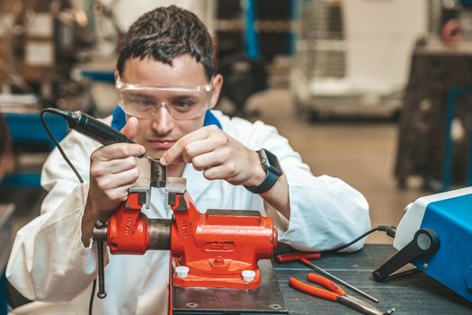 student of technical school on practical exam when working with vise and electric grinder.