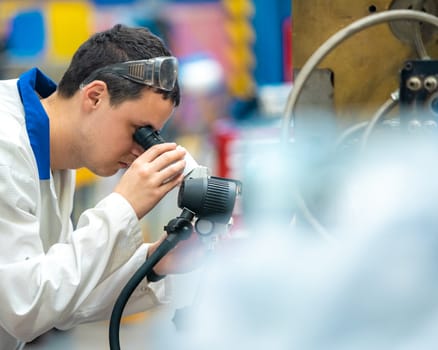 the engineer checks the correct setting of the metal mold for castings in the factory using a microscope.