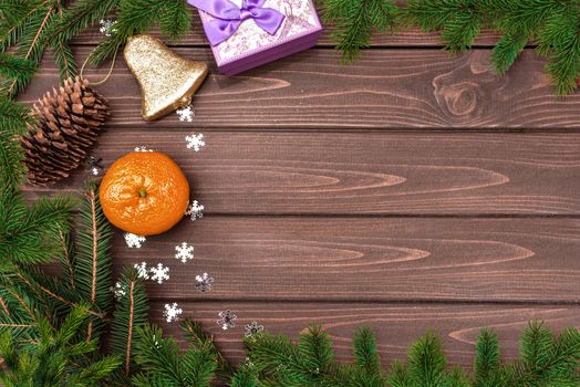 Christmas background, Fir branch, cones , orange, bell and gifts on a wooden table. Space for text. View from above. Christmas atmosphere