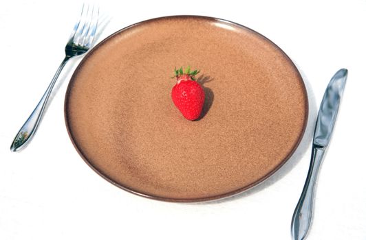 Brown plate with one fresh strawberry