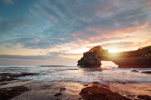 Sunset near famous tourist landmark of Bali island - Tanah Lot & Batu Bolong temple. Long exposure effect, Bali Indonesia. Tropical nature landscape of Indonesia, Bali.