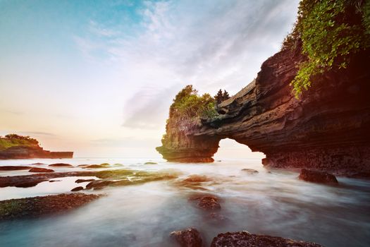 Sunset near famous tourist landmark of Bali island - Tanah Lot & Batu Bolong temple. Long exposure effect, Bali Indonesia. Tropical nature landscape of Indonesia, Bali.