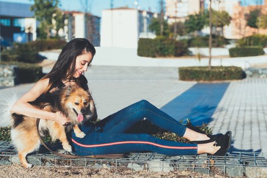 attractive young  woman sitting with dog in the city