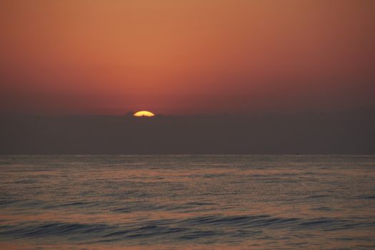 Sunrise in the ocean, the sun appears. Dark waves, lonely, unsuspecting