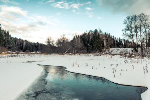 Snow fell on the dry yellow grass by the river. Beautiful winter landscape. Bank of the river after the first snowfall. Dry grass in the snow near the pond.