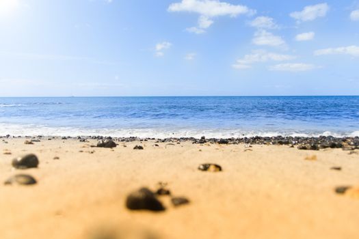 waves and blue waters. Beach with black stones and the sun.