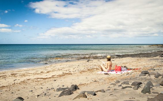 west coast of Fuerteventura, Canary Islands, Bikini Girl Reading book in relax mood in a lonely beach