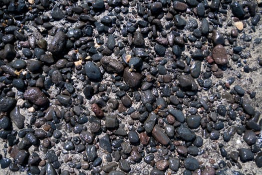 Volcanic dark stones wet on golden sand. Suitable for backgrounds
