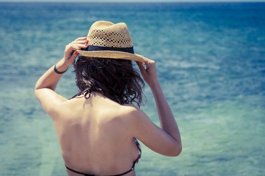 Beach vacation. Beautiful woman in sunhat and bikini looking at the beach on a hot summer day. Photo from Fuerteventura Island, Spain