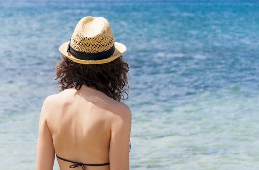 Beach vacation. Beautiful woman in sunhat and bikini looking view of beach ocean on hot summer day. Photo from Fuerteventura Island, Spain.