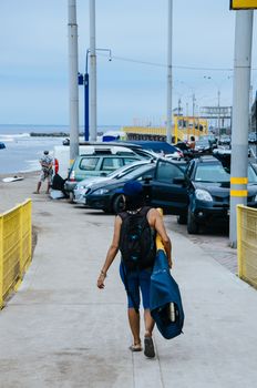 Young surfer woman walking towards the sea