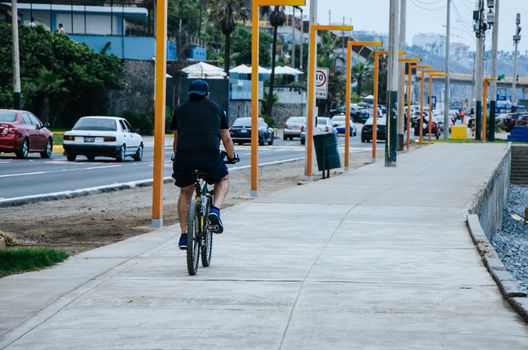 Man on his bicycle walking through the sea coast