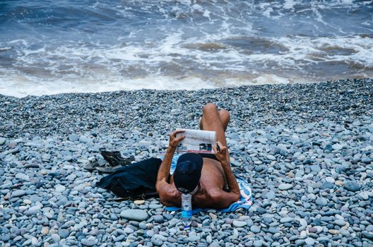 Man reading the newspaper on the beach and enjoying the summer