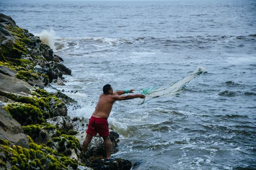 Fisherman throwing his net to catch some fish