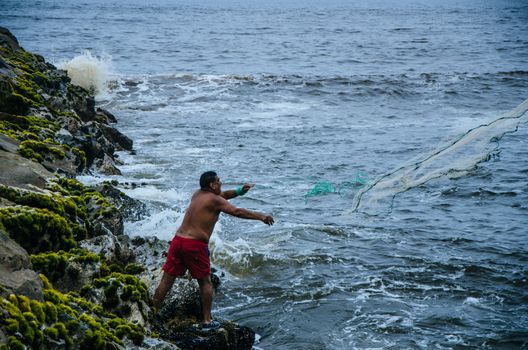 Fisherman throwing his net to catch some fish