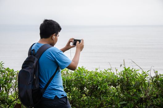 Child taking photo with his smartphone to the sea