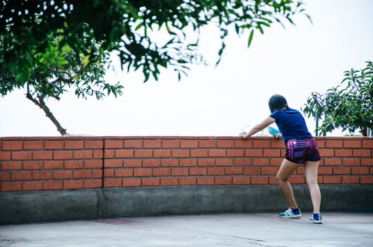 Woman lying on a wall doing exercises outdoors