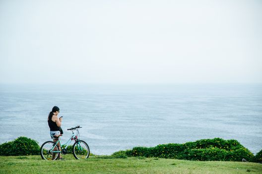 Woman with her bicycle in front of the sea