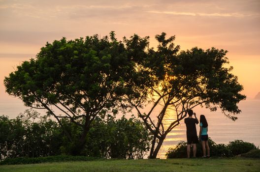 A couple taking pictures to the sea in the afternoon