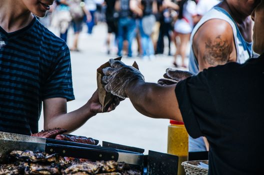 Hamburger seller handing a hamburger to a buyer