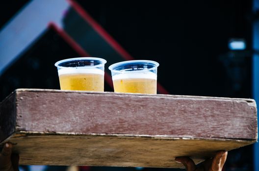 Two plastic cups with beer in a wooden box