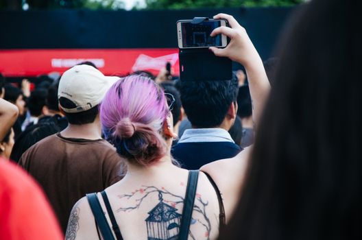 A woman taking pictures with her cell phone at the concert