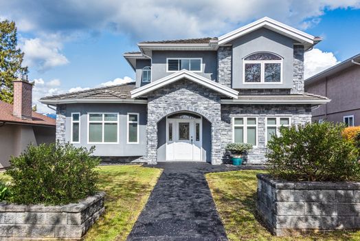 Nice residential house with stone texture walls and stone walls on front yard. Big family house with landscaped front yard