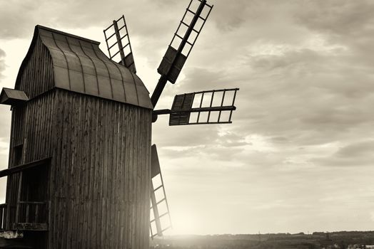 Old windmill standing alone in the field with the blue sky. sepia filter