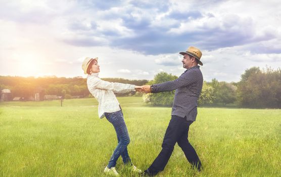 a portrait of a happy middle-aged couple holding hands in the green field.