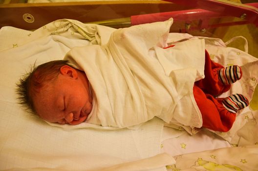 New born baby - girl in a hospital. Newborn baby girl - 3,5 hours old - with warm clothes.